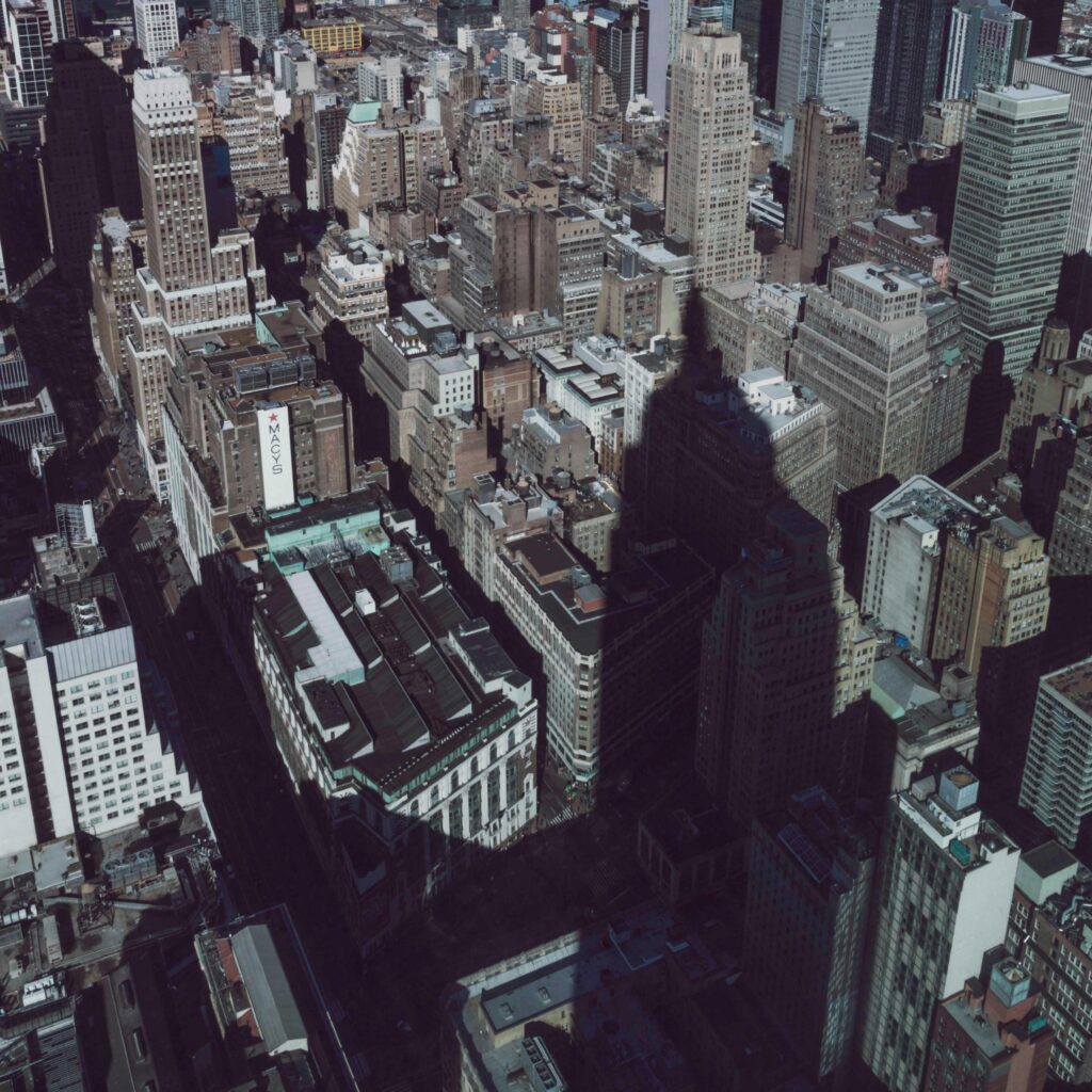 Aerial shot of New York City showing dramatic skyscraper shadows and dense urban architecture.